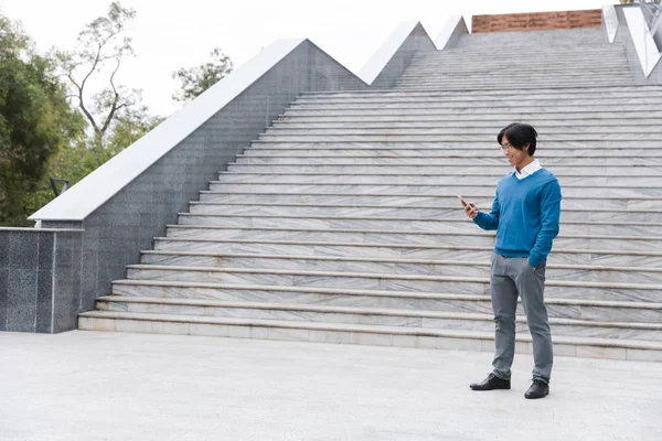 Sonriendo Joven Asiático Hombre Hablando Teléfono Móvil Mientras Que Pie —  Fotos de Stock