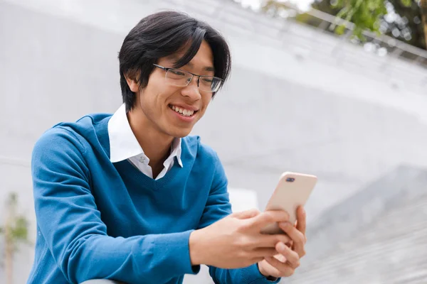 Jonge Aziatische Man Praten Mobiele Telefoon Zittend Trap Buiten Glimlachen — Stockfoto