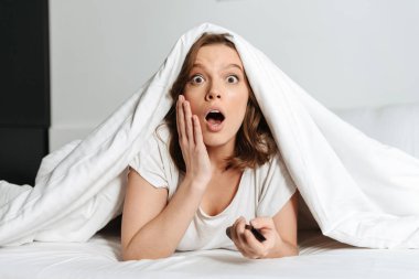 Çekici şok genç kadın evde yatakta yatan Tv izlerken