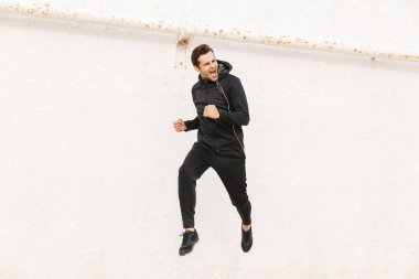 Görüntü siyah spor giyim ve kulaklık beyaz duvar açık çalışan Avrupa insanın 30s