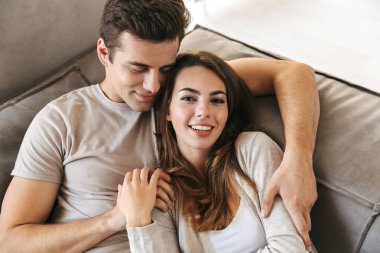 Evde bir kanepede döşenmesi, kucaklayan mutlu genç çift