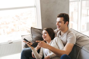 TV izlerken bir kanepede evde oturan mutlu genç çift