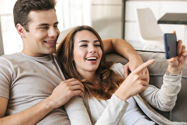 Happy Young Couple Sitting Couch Home Using Mobile Phone — Stock Photo, Image