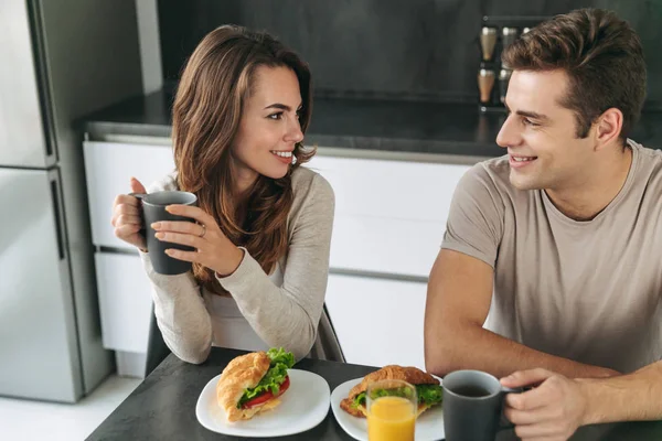 キッチンで朝の朝食を食べた幸せな笑みを浮かべてカップル — ストック写真