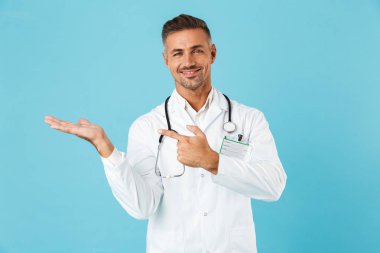 Mavi arka plan üzerinde izole ayakta stetoskop ile gülümseyen tıp doktoru portresi
