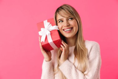 Hediye kutusu açık pembe arka plan üzerinde izole neşeli genç sarışın kız ayakta