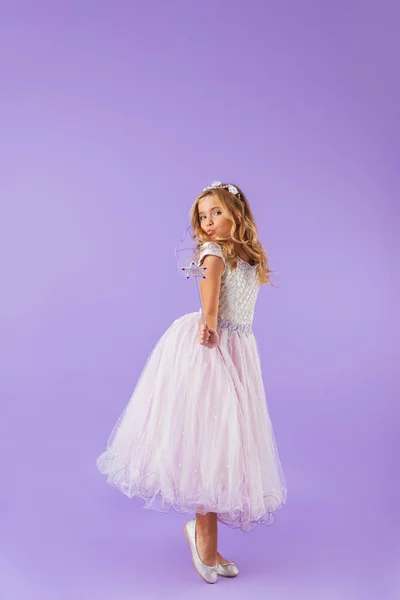 魔法の杖を保持している 紫色の背景に分離されたプリンセスのドレスを着て笑顔のかわいい女の子の完全な長さの肖像画 — ストック写真