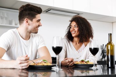 Evde bir romantik akşam yemeği, şarap kırmızı içme ve makarna yemek güzel genç çok ırklı çift