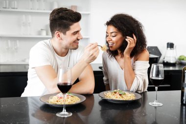Evde bir romantik akşam yemeği, şarap kırmızı içme ve makarna yemek güzel genç çok ırklı çift