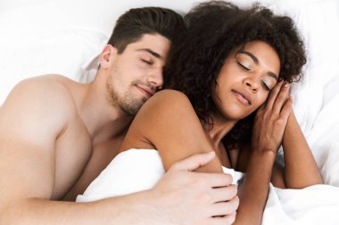 Güzel mutlu genç çok ırklı çift battaniye altında yatakta uyuyan kadın rahatlatıcı