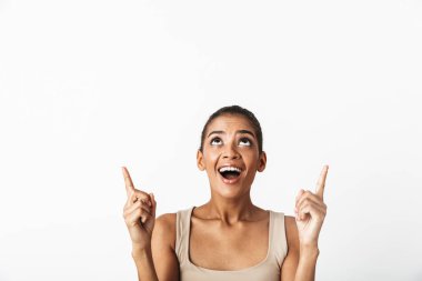 Güzel genç Afrikalı kadın kayıtsızca giyinmiş ayakta beyaz arka plan üzerinde izole kopya alanı, parmakları işaret