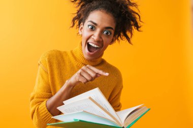 Sarı arka plan üzerinde izole bir kitap kazak giyen neşeli Afrika kadın