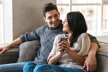 Evde bir kanepede oturan, Tv izlerken, çay içme mutlu genç çift