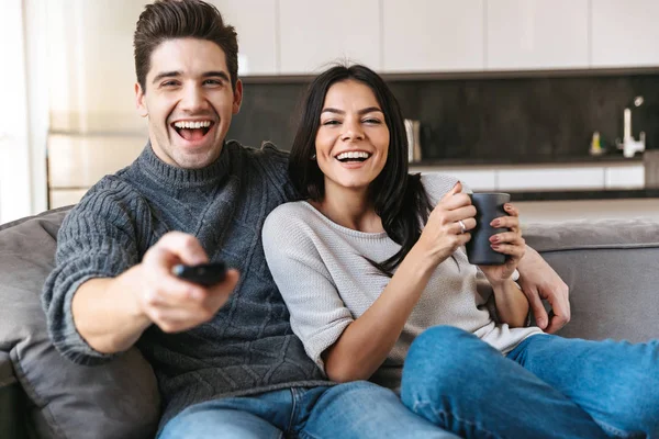 Pareja Joven Feliz Sentada Sofá Casa Viendo Televisión Tomando — Foto de Stock