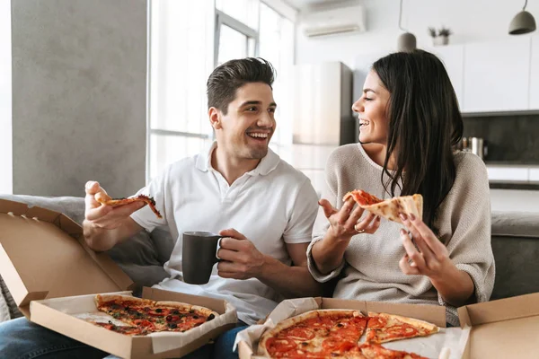 Wesoły Młoda Para Siedzi Kanapie Domu Jedzenie Pizzy Oglądanie Telewizji — Zdjęcie stockowe