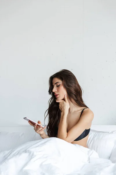 Beautiful Upset Young Woman Wearing Black Lingerie Using Mobile Phone — Stock Photo, Image