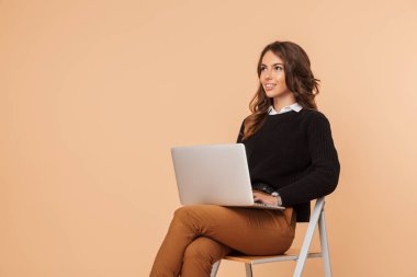 Dizüstü bilgisayar kullanan taburede oturan güzel bir şaşırtıcı genç kadın poz görüntü izole.