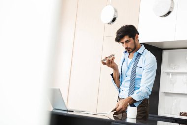 Ciddi konsantre genç iş adamı tarafından cep telefonu iş belgeleri ile konuşurken mutfak at görüntüsünü.