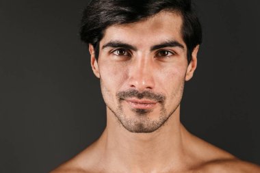 Karanlık duvar arka plan üzerinde izole görüntüsünü poz bir çıplak gülümseyen yakışıklı genç.