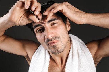 Yakışıklı bir genç adam poz görüntü üzerinde karanlık duvar arka plan doğru kaşları formu cımbız ile izole.