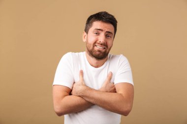 Karışık bir genç adam portresi raslantı bej renkli arka plan üzerinde izole ayakta giyinmiş