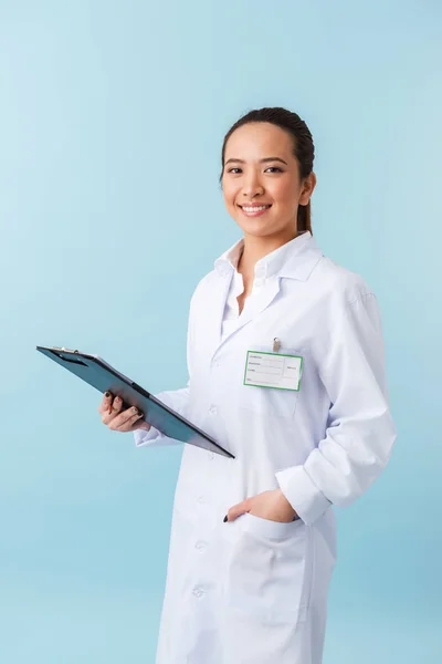 水色の壁背景持株クリップボード上分離されたポーズ陽気な若い女医の写真 — ストック写真