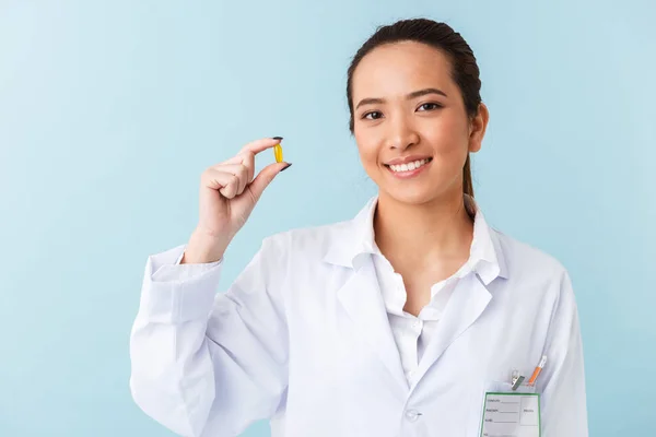 薬を保持している水色の壁の背景の上分離されたポーズの若い女性医師の写真 — ストック写真