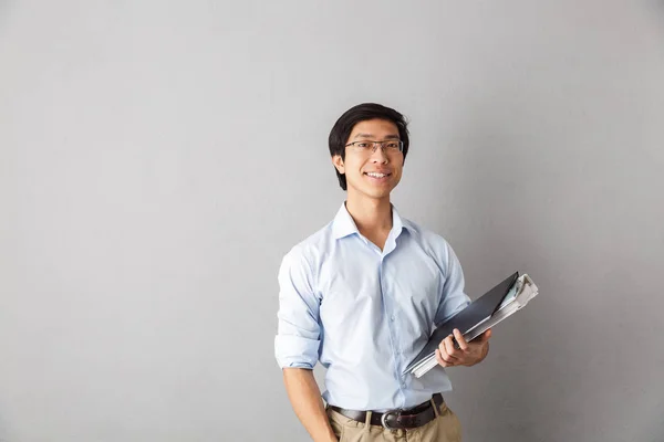 Feliz Asiático Hombre Pie Aislado Sobre Gris Fondo Llevando Carpetas — Foto de Stock