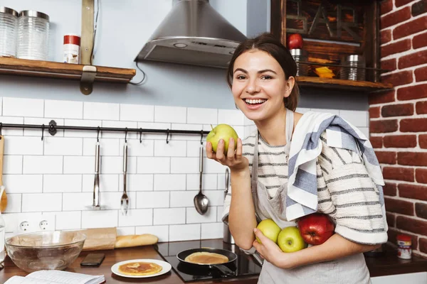 Szczęśliwy Młoda Kobieta Stoi Kuchni Domu Trzymając Jabłka — Zdjęcie stockowe