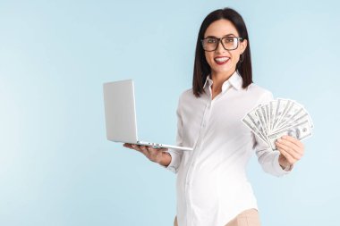 Para tutan dizüstü bilgisayar kullanan mavi duvar arka plan üzerinde izole bir güzel genç hamile iş kadını görüntüsünü.