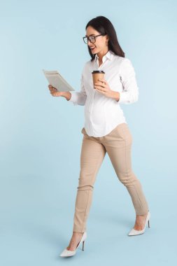 Kahve içme gazete okuyan mavi duvar arka plan üzerinde bir güzel genç iş kadını görüntü izole.