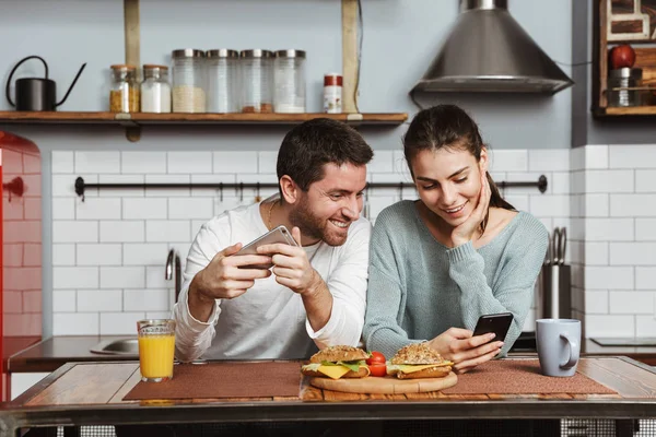 Felice Giovane Coppia Seduta Cucina Durante Colazione Casa Utilizzando Telefono — Foto Stock