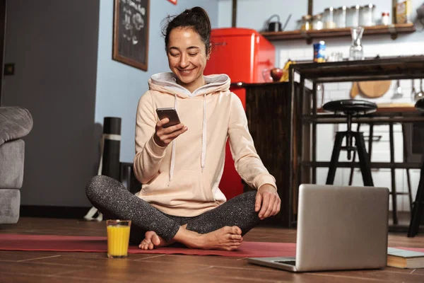 Glad Frisk Kvinna Sitter Fitness Matta Och Pratar Mobiltelefonen Hemma — Stockfoto