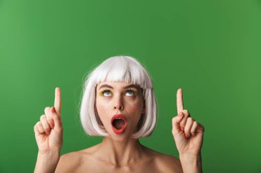 Kopya alanı parmak işaret kısa beyaz saç yeşil arka plan üzerinde izole ayakta giyen çekici genç üstsüz kadın