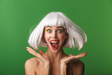 Yeşil arka plan üzerinde izole kısa beyaz saç ayakta giyen çekici genç üstsüz kadın kutluyor