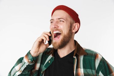 Şapka ve beyaz arka plan üzerinde izole ayakta iken cep telefonuyla konuşurken kareli gömlek giyen olumlu adam görüntüsünü