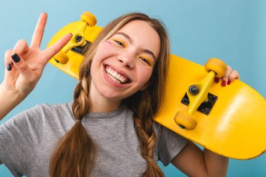 Kaykay holding neşeli şirin kız mavi arka plan üzerinde izole ayakta