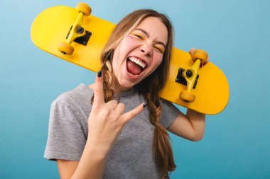 Kaykay holding neşeli şirin kız mavi arka plan üzerinde izole ayakta