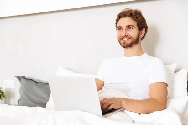 Imagen Guapo Joven Barbudo Cama Casa Usando Ordenador Portátil —  Fotos de Stock