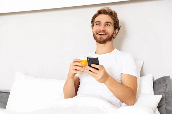 Yakışıklı Bir Genç Sakallı Adam Yatakta Görüntüsünü Evde Cep Telefonuyla — Stok fotoğraf