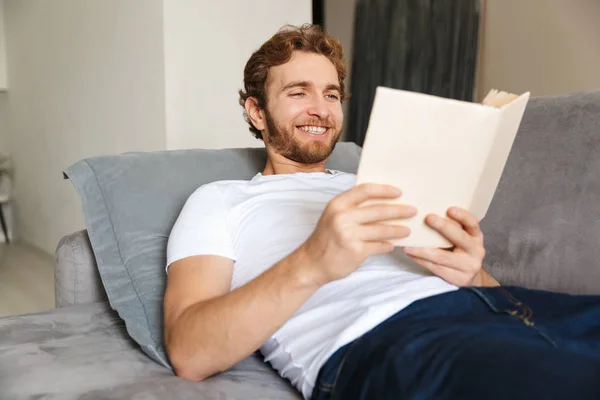 Imagem Belo Jovem Barbudo Sofá Casa Livro Leitura — Fotografia de Stock