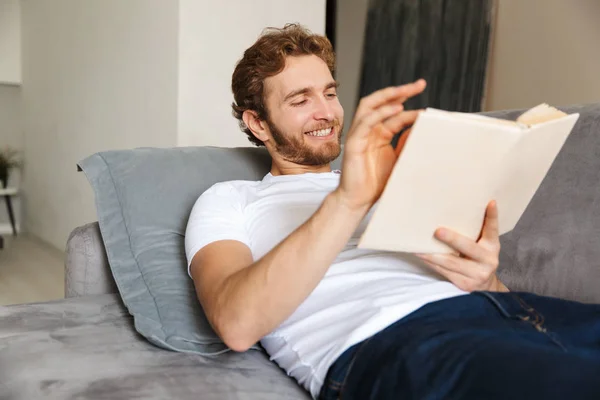 Immagine Bel Giovane Barbuto Sul Divano Casa Leggere Libro — Foto Stock