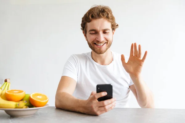 Foto Joven Barbudo Feliz Mesa Casa Hablando Por Teléfono Móvil — Foto de Stock