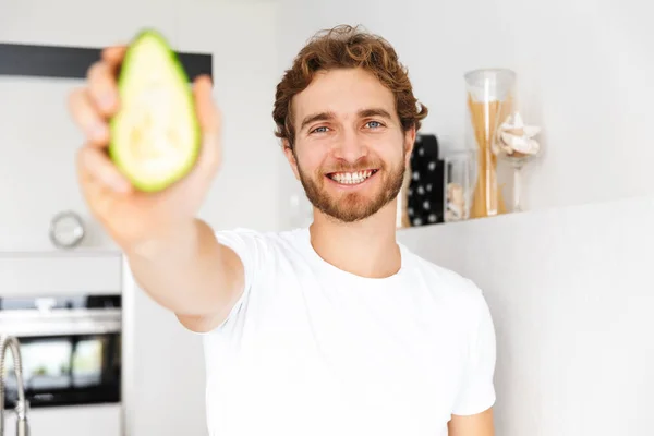 Foto Stilig Ung Man Kök Hem Matlagning Innehav Avokado — Stockfoto