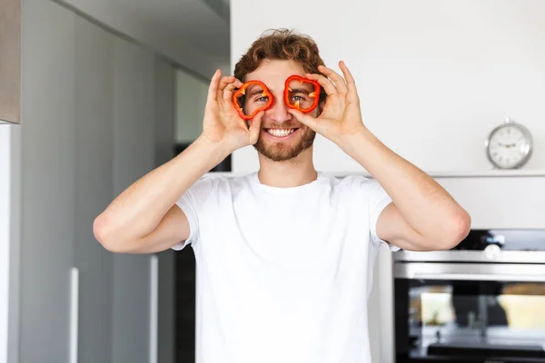 Foto Stilig Ung Man Kök Hem Matlagning Innehav Peppar Paprika — Stockfoto