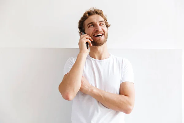 Sonriente Joven Hablando Por Teléfono Móvil Parado Pared Casa — Foto de Stock