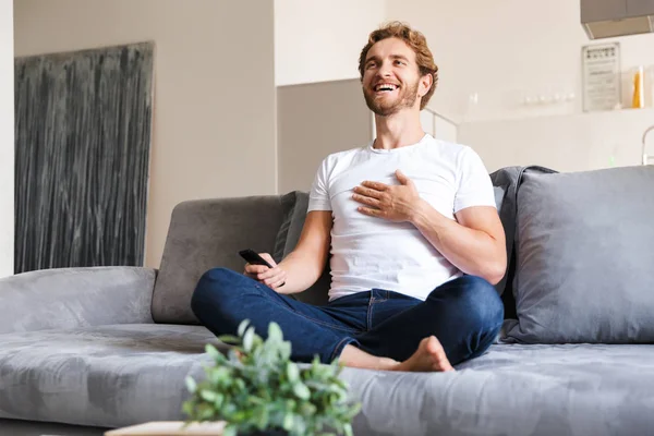 Photo Handsome Happy Young Man Sofa Home Holding Remote Control — Stock Photo, Image