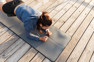 Plajda bir fitness mat tahta egzersizleri yapıyor sporcumuz konsantre