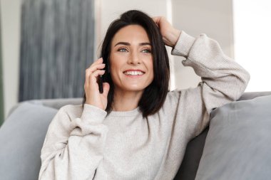 Güzel genç kadın evde, bir kanepede rahatlatıcı istimal hareket eden telefon
