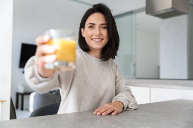 Resim parlak modern odasında istirahat ederken güzel kadın 30'lu yaşlarda içki portakal suyu